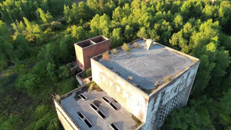 Drone-flying-over-an-overgrown,-derelict,-coal-mining-building