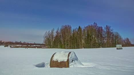 Static-shot-of-snow-covered-fields-with-round-hay-bales-during-winter-season-during-daytime-in-timelapse