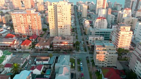Aerial-dolly-in-of-ViÃ±a-del-Mar-neighborhood-houses-and-buildings-with-traffic-in-avenue-in-commercial-area,-Chile