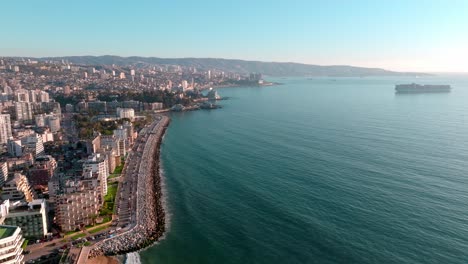 Aerial-dolly-in-of-Peru-Avenue-seaside-boulevard-near-turquoise-sea,-ViÃ±a-del-Mar-buildings-and-mountains,-Chile