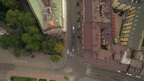 Tram-turning-around-the-corner-in-Krakow-center,-Poland,-aerial-top-down-view