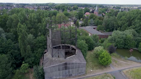 Old-dilapidated-cooling-tower-on-a-cycle-path-for-industry-with-the-church-tower-of-the-village-of-Ilsede-in-Germany-in-the-background