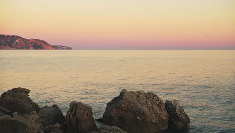 Aerial-Drone-View-of-Mediterranean-Coast-at-Pink-Sunset-in-Spain-at-Nerja,-Costa-Del-Sol-in-Andalusia-,-Europe,-Ocean-Sea-Water,-Horizon-and-Clear-Sky-Background-with-Copy-Space