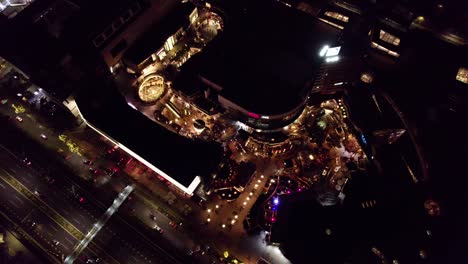 Aerial-top-down-orbit-of-Parque-Arauco-luxurious-Shopping-Mall-illuminated-at-night,-Las-Condes,-Santiago,-Chile