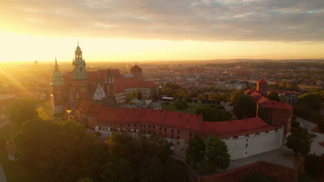 Aufsteigende-Luftaufnahme-Der-Gewaltigen-Beleuchtung-Des-Königlichen-Schlosses-Wawel-Während-Des-Goldenen-Sonnenaufgangs-In-Der-Stadt-Krakau