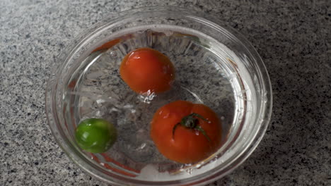 Tomates-Rojos-Maduros,-Pimiento-Verde-Y-Lima-Empapados-En-El-Recipiente-Con-Agua