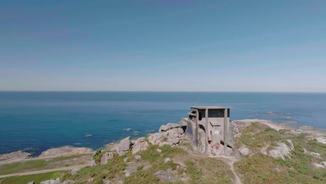 Aerial-drone-forward-moving-shot-of-an-old-abandoned-watchtower-used-in-the-spanish-civil-war-overlooking-the-beautiful-coastline-at-daytime