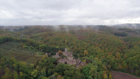 Remote-medieval-castle-in-Tuscany-woodland-on-hill-during-cloudy-day,-aerial