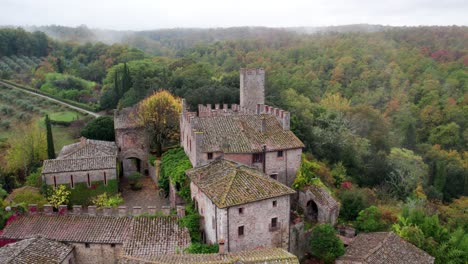 Old-Italian-style-brick-buildings-in-forest-environment-on-cloudy-day,-aerial