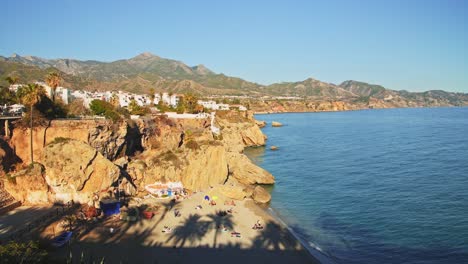 Aerial-Drone-View-of-Beautiful-Beach-on-Mediterranean-Coast-of-Spain-at-Nerja,-Costa-Del-Sol-in-Andalusia-,-Mountains-and-Blue-Ocean-Sea-Water-on-Sunny-Day-With-Clear-Blue-Sky-in-Europe-1