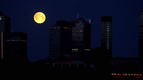 Ein-Orangefarbener-Vollmond-Umkreist-Und-Versteckt-Sich-Hinter-Wolkenkratzern-Im-Nächtlichen-Zentrum-Von-Warschau