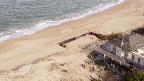 Luftaufnahme-Aus-Der-Umlaufbahn-Von-Arbeitern,-Die-Ein-Neues-Strandhaus-Am-Strand-Von-Jose-Ignacio-In-Uruguay-Herstellen