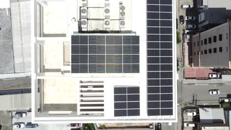 Top-shot-of-drone-capturing-solar-panels-on-tall-residential-building,-renewable-energy-concept