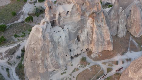Aerial-view-of-horses-walking-between-fairy-chimney-rock-formations-at-sunset-Cappadocia-turkey