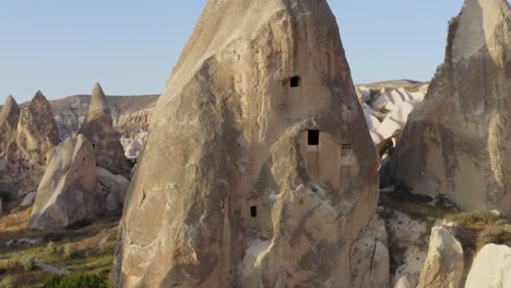 Flying-towards-windows-carved-into-fairy-chimney-rock-formations-aerial-Cappadocia-turkey-view