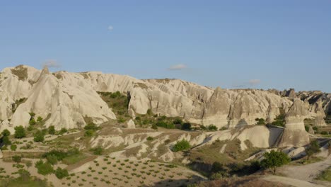 Drone-flying-over-green-traditional-farmland-field-to-reveal-natural-brown-rock-formations-Cappadocia-turkey