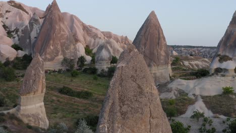 Rotation-around-close-up-of-fairy-chimney-natural-rock-formation-above-grass-fields-in-Cappadocia-turkey