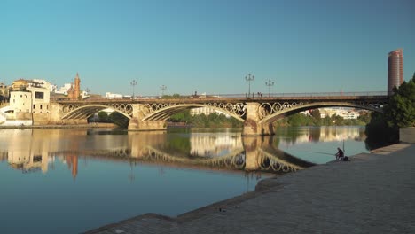 Sevilla-Beherbergt-Spiegelung-Im-Fluss-Guadalquivir-Am-Frühen-Morgen-Und-Fischer-Mit-Triana-brücke-Als-Hintergrund