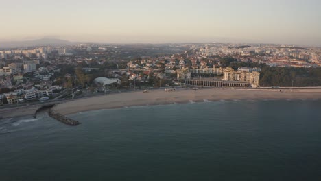 Aerial-view-over-Santo-amaro-beach-in-Oeiras,-sunset-in-Portugal---drone-shot