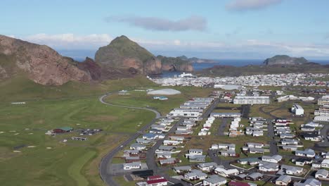 Heimaey-nordic-island-with-small-remote-town-and-green-golf-course,-aerial