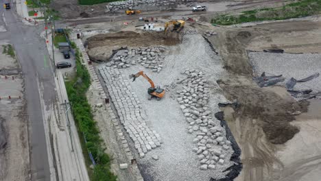 Excavadora-Con-Garfio-Construyendo-Una-Pared-De-Roca-Con-Bloques-De-Piedra-Caliza-Cincelados-En-El-Sitio-De-Construcción