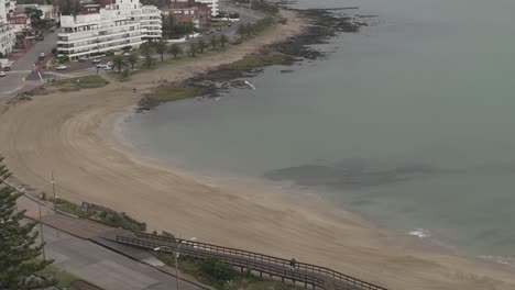 Time-lapse-of-person-with-dog-walking-on-Punta-del-Este-beach-in-Uruguay-on-cloudy-day