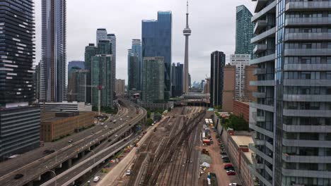 Toma-De-Drones-De-Las-Vías-Del-Tren-De-La-Estación-Union-Del-Centro-De-Toronto-Al-Lado-De-La-Autopista-Gardiner-Con-La-Torre-Cn-En-Segundo-Plano