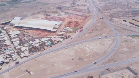 Impressive-aerial-drone-shot-of-a-Peruvian-highway-with-cars-circulating-and-a-factory