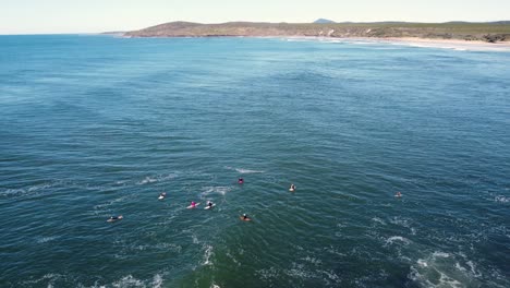 Drone-aerial-shot-of-local-surfers-waiting-in-line-up-travel-tourism-peaceful-nature-Pacific-Ocean-North-Coast-Yamba-Ballina-NSW-Australia-4K