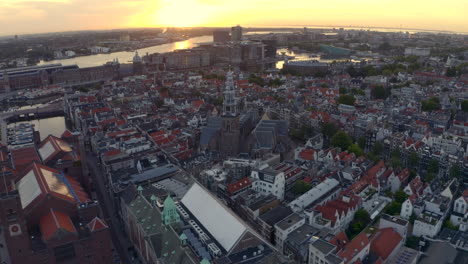 Low-establishing-drone-shot-over-central-Amsterdam-De-Oude-kerk-church-at-sunrise