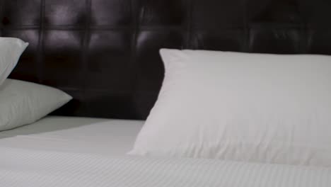 White-and-black-hotel-bedroom,-clean-and-comfortable-pillows,-sheets,-pan-right-close-up