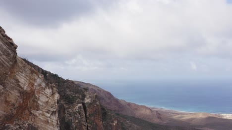 Breathtaking-shot-of-the-stone-mountains-on-Socotra-Island-and-the-Indian-Ocean-coast,-Drone-camera-movement