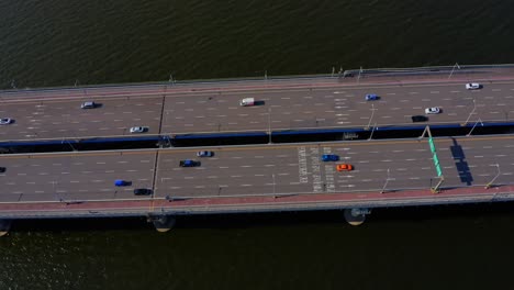 Drone-shot-flying-above-a-bridge-crossing-a-river-with-a-lot-of-traffic-on-it