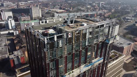 Aerial-drone-flight-around-the-rooftop-of-a-new-tower-under-development-on-Oxford-Road-in-Manchester-City-Centre-showing-a-view-of-the-surrounding-city-buildings