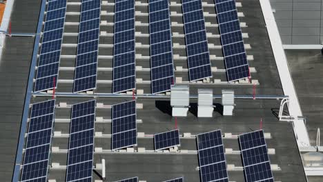 Aerial-view-of-solar-panels-on-a-building-roof,-summer-in-Finland---tilt,-drone-shot