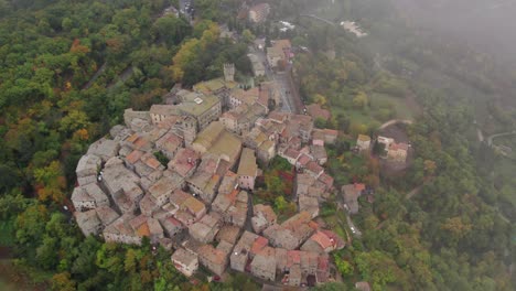 Flying-through-light-cloud-with-view-of-medieval-town-in-Tuscany,-aerial
