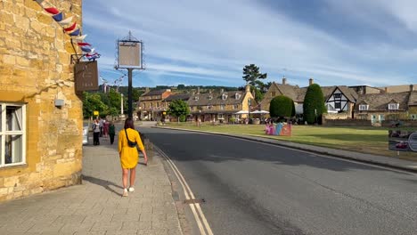 Girl-walking-the-Cotswold-Way-along-the-town-centre-of-Broadway---England-UK
