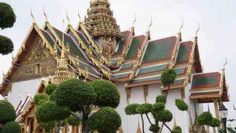 The-beautiful-green-garden-with-a-golden-and-impressive-temple-in-the-background,-located-in-Grand-Palace-in-Bangkok