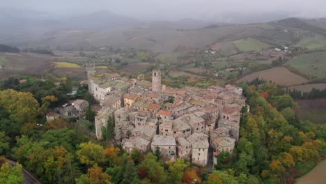 Ancient-medieval-comune-in-Italy-countryside-on-cloudy-day,-aerial