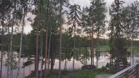 Woman-enjoying-Lake-View-at-Nordic-Summer-Cabin-with-Sunset,-Dolly-Shot