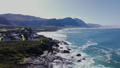 Drone-tilt-up-over-tidal-pool-reveals-scenic-Hermanus-coastline,-Overstrand