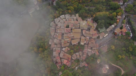 San-Casciano-dei-Bagni-old-town-seen-from-above-through-mist,-aerial