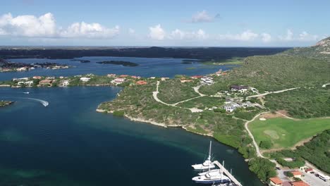 Vista-Aérea-De-La-Isla-Con-Botes-Y-Montañas-Cancha-De-Golf-Vista-Al-Mar-Veleros-Puerto-Deportivo-1