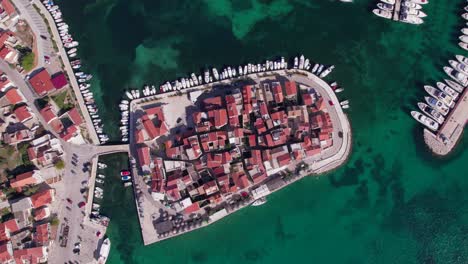 Top-down-of-red-roof-medieval-town-on-peninsula-in-Adriatic-Sea,-Croatia