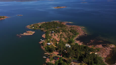 Aerial-view-around-a-island-peninsula-with-summer-houses-in-sunny-Degersand,-Aland---circling,-drone-shot