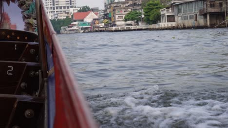 A-longtail-boat-is-splashing-in-the-water-on-one-of-the-charming-rivers-of-Bangkok-in-Thailand
