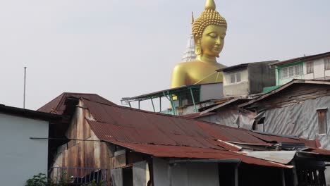 An-old-and-worn-out-neighborhood-in-the-backwaters-of-Bangkok,-in-the-poor-part-of-the-city-in-the-capital-of-Thailand-in-Asia,-with-a-huge-buddha-statue-in-the-background