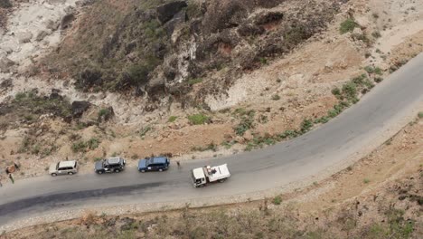 Truck-passes-three-parked-off-roads-on-a-narrow-,-winding-asphalt-road-in-the-mountains-of-Socotra-Island