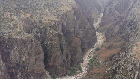 Camera-rises-above-a-deep-canyon-with-a-dry-riverbed