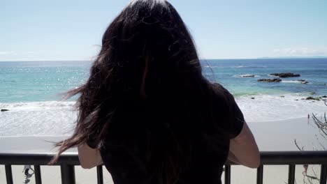 Woman-looking-over-at-the-sea,-standing-on-the-view-point-on-the-beach